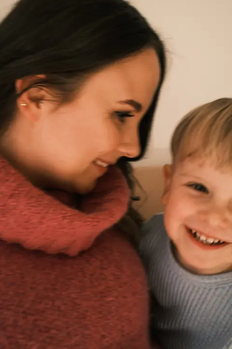Mama i synek uśmiechają się do siebie, policzek przy policzku